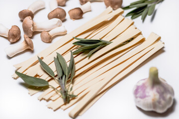 Handgemachte Spaghetti mit Salbei, Kräuterseitlingen und Knoblauch vor weissem Hintergrund