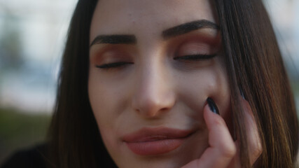 Close up portrait of young woman on the street happy eyes closed looking at camera. Flirting feelings