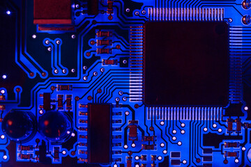 Close-up of a modern blue printed circuit board (PCB) with stripes of conductors between a...