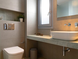 Modern style interior of small bathroom tiled gray stone with window, vessel bowl sink, mirror back...
