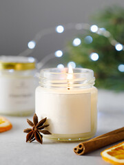 Aroma candle in a glass jar with the aroma of spices. The aroma of mulled wine. winter atmosphere with bokeh. winter scents. Star anise, cinnamon sticks, citrus fruits. 