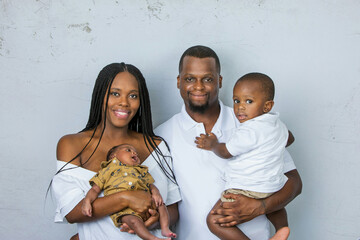 A beautiful African-American young family with two children. The oldest son is a toddler and the new infant newborn son is only a few weeks old.