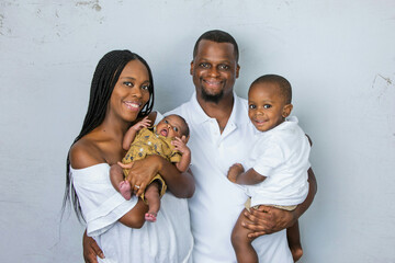 A beautiful African-American young family with two children. The oldest son is a toddler and the new infant newborn son is only a few weeks old.