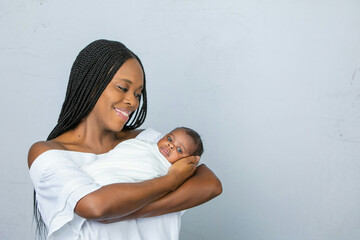 A beautiful African-American new mom holding and cradling her newborn son and looking at him with love and affection