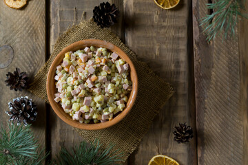 Obraz na płótnie Canvas Traditional Olivier salad russian in a bowl on a wooden background. Festive Russian cuisine. Top view. Copy space. Rustic style. Horizontal orientation.