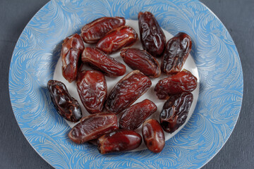 A blue plate with dates on grey background in top view. Closeup. Flatlay