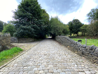 Looking up, Lee Lane with stone cobbles, and dry stone walls, on a cloudy day in, Shibden Valley, Halifax, UK