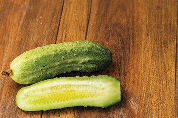 Close up view of cucumber cut in two parts isolated on wooden background. Fresh vegetables and healthy eating concept.