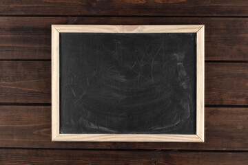 black dirty chalkboard in a frame on a dark wooden background, copy space, top view