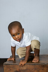 Adorable African-American toddler age little boy playing and climbing on a crate
