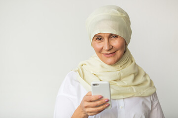 beautiful adult woman aged in a muslim headscarf with a mobile phone