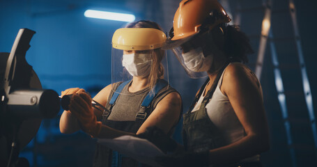 Factory female workers measuring diameters of pipe piece