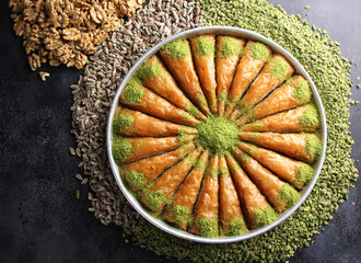 Oriental sweets. Pahlava with nuts, pistachio in a large dish on a black table. Turkish dessert. Background image, copy space, horizontal, top view, flatlay