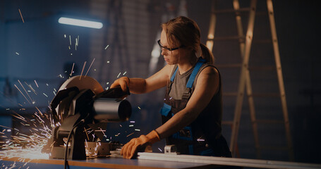 Obraz na płótnie Canvas Female worker working with metal cutting saw
