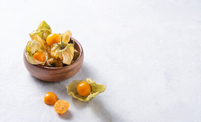fresh  yellow peruvana physalis in wooden bowl  on white table