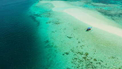 Sandy beach with tourists among turquoise waters and coral reefs. Mansalangan sandbar. Beach at the atoll. Summer and travel vacation concept. Balabac, Palawan, Philippines.