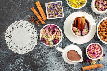top view of herbal tea with melted chocolate and dry flowers and a piece of lace on grey ground