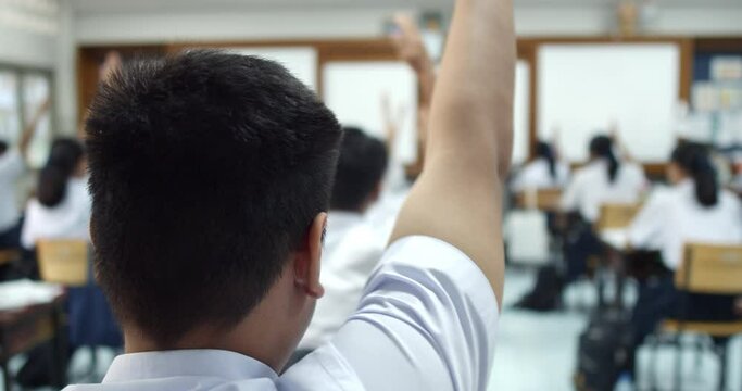 Slow motion of Asian high school students in white uniform actively study science by raising their hands to answer questions that teachers ask them  in classroom.