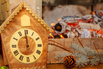 Fototapeta na wymiar Retro clock with cuckoo with Roman numerals on the background of a fireplace with fire.
