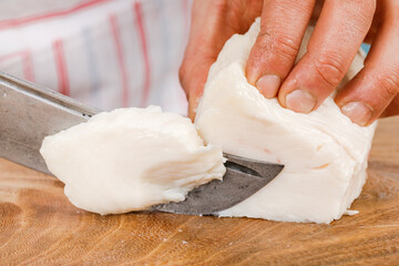 Fototapeta na wymiar Cook cuts raw pork fat into small pieces on a wooden cutting Board.