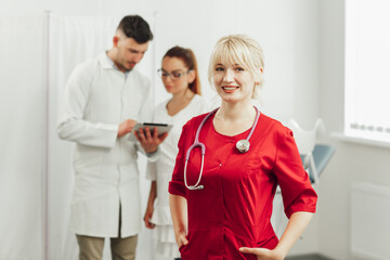 Obraz premium Close-up portrait of a smiling female doctor in a red uniform with a stethoscope.