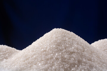 Heap of granulated sugar on a blue background. Copy space.