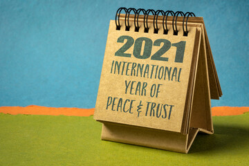2021 - the International Year of Peace and Trust declared by United Nations, text in a desktop spiral calendar against abstract paper landscape