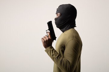 robber in a balaclava with a weapon in his hand on a white background