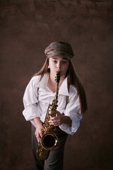 Obraz na płótnie Canvas girl plays jazz saxophone. talented child artist musician in a hat, shirt and trousers