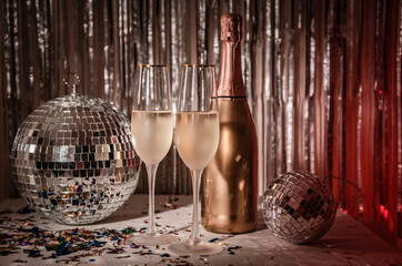 Glasses of champagne and a bottle,  a disco ball on a shining gold surface. New Years Eve party...