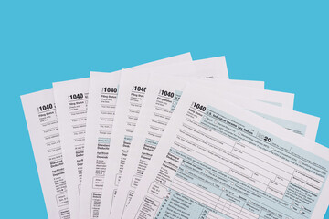 Tax concept. US tax forms on blue background. 1040 forms to fill in April.
