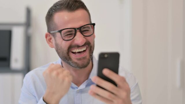 Portrait of Middle Aged Man Excited by Success on Smartphone 