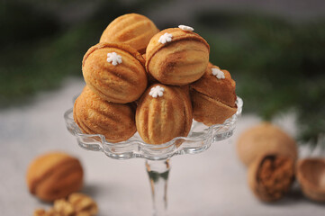 Nuts biscuits stuffed with boiled condensed milk.  Next to the vase are walnuts in shell and without shell. Close-up.