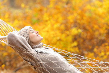 Happy woman lying on a hammock in fall season