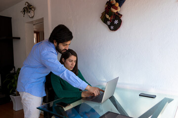 Man in blue shirt explaining something to a sitting young woman in the computer