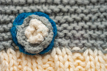 Knitted pattern of threads in two colors and styles. Small flower on a scarf.