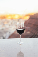 A glass of red wine on a rooftop terrace, city view on the background