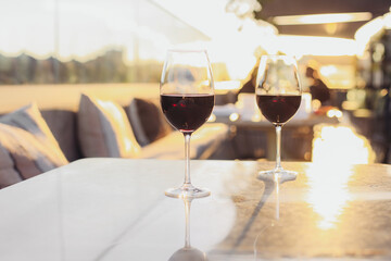 Two glasses of red wine on a terrace table, sunset light