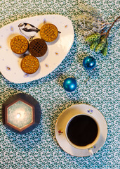 Cup of coffee, candle, cookies and Christmas decorations on a blue background