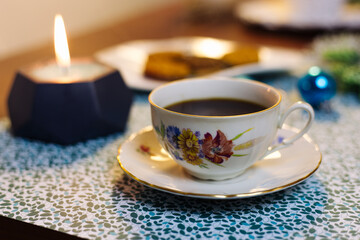 Cup of coffee, candle, cookies and Christmas decorations on a blue background
