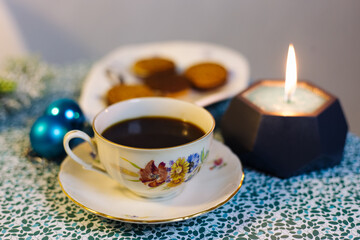 Obraz na płótnie Canvas Cup of coffee, candle, cookies and Christmas decorations on a blue background