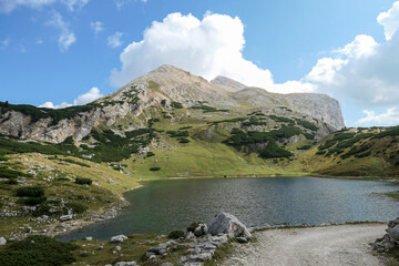 A panoramic view on the Le de Limo in Italian Dolomites. The lake has many shades, from turquoise to navy blue. High mountain behind it. High Alpine lake. Wandering and discovering remote places
