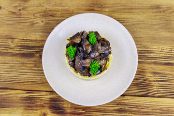 Tasty layered salad with roasted mushrooms, potato, eggs, cheese and mayonnaise on wooden table. Top view