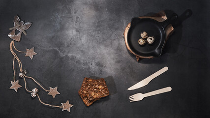raw quail eggs in a black round pan, next to bread and a disposable wooden fork and knife....