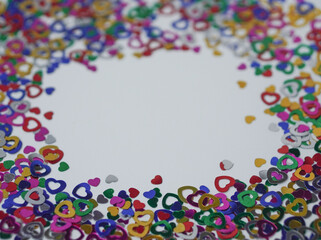 Heart shape colorful confetti frame, border on white background. Happy Valentines Day. Selective focus on a middle part of image.