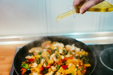 unrecognizable man preparing vegetables food in pan. Adding olive oil. Healthy food