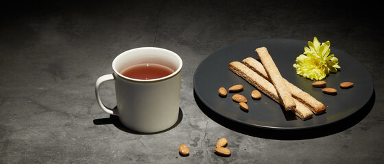 Obraz na płótnie Canvas a cup of english tea with cookies on a plate on a dark background, a dark photo of food. tea relaxation
