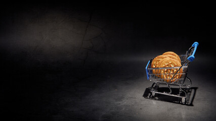 Miniature shopping basket with cookies on a dark background. Grocery Shopping. Place for your text