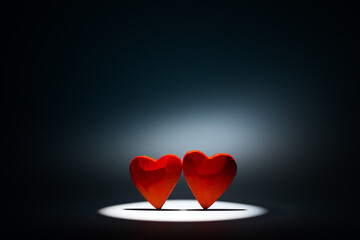 Two small red hearts in round beam of light. Valentine's day background.