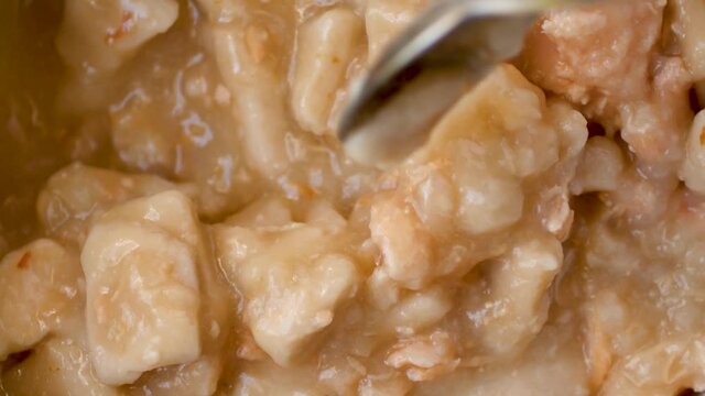Overhead close video of microwaved canned chicken dumpling stew being stirred.